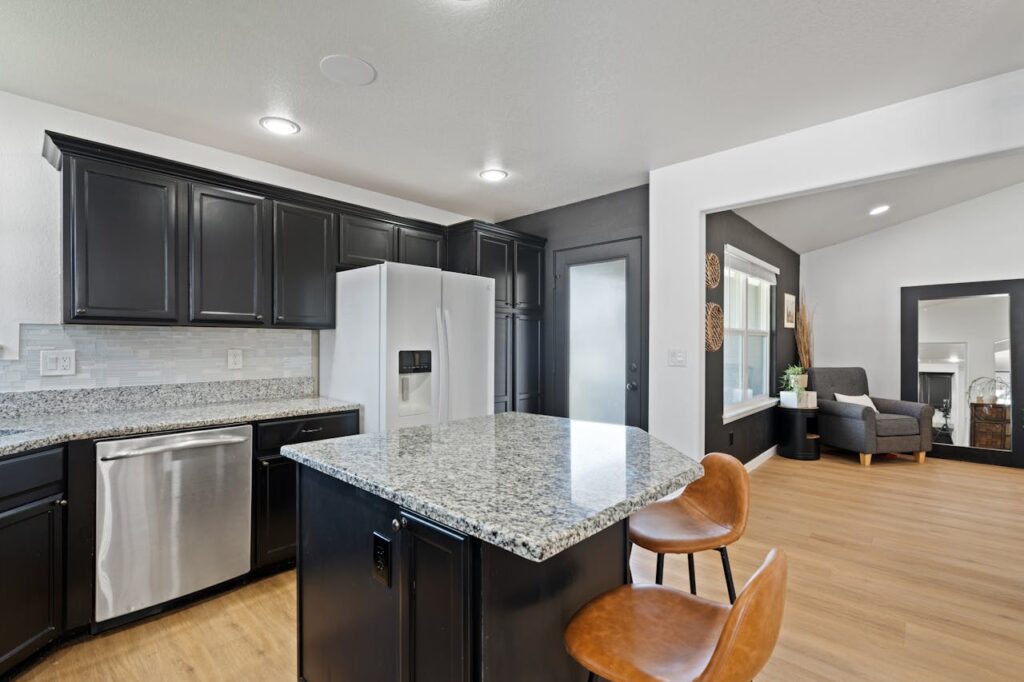 Sleek modern kitchen featuring granite countertops, black cabinets, and an open design.