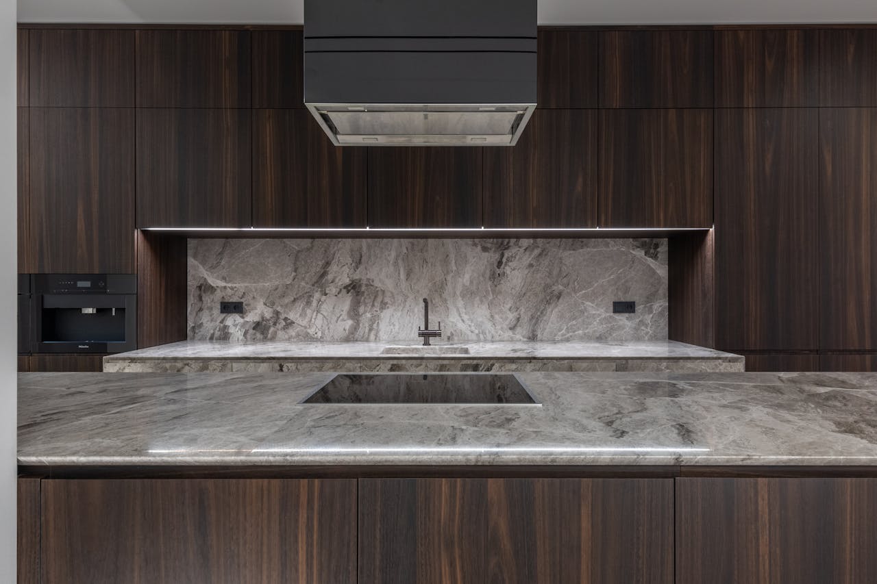 Sleek modern kitchen interior featuring marble countertops and dark wood cabinets.
